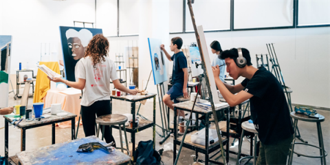 An art studio full of students focusing on work on canvases 
