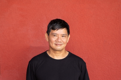 Simon Leung in front of red wall