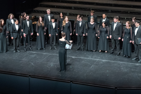 A choir being conducted on stage