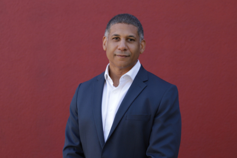 Person in blue suit in front of red background