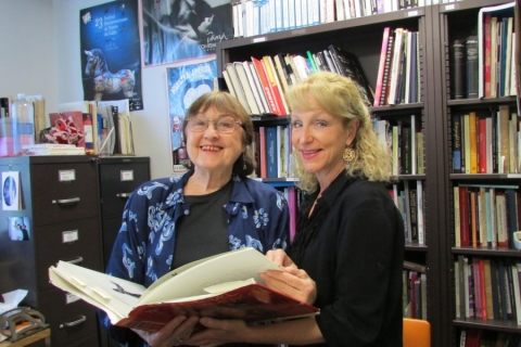 Two women holding a large book